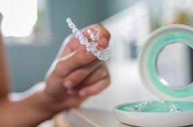Person taking Invisalign aligner out of its storage case