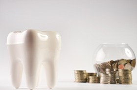 Tooth model in foreground, stacks of coins in background