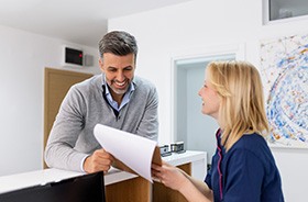 Dental team member and patient reviewing paperwork