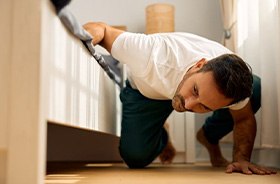Man looking under bed for lost item