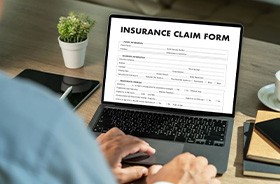 Person filling out insurance claim form on laptop