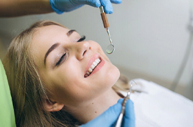 Happy young woman getting checkup from family dentist